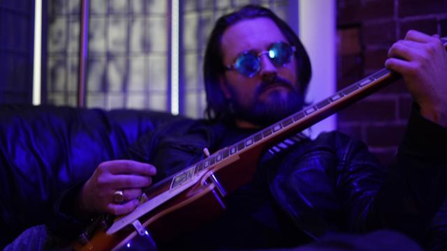 Yahoshua under blue light, playing guitar
